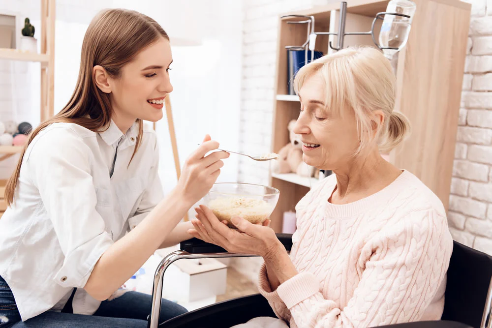Lady helping an elderly with her food